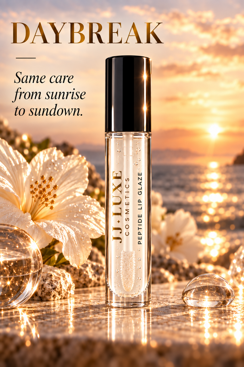 JJ Luxe Cosmetics Daybreak editorial by the sea with glossy black cap, reflective gold JJ Luxe Cosmetics branding, black Peptide Lip Glaze lettering, and Same care from sunrise to sundown messaging.