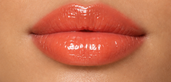JJ Luxe Cosmetics Heatwave Peptide Lip Glaze on light medium complexion lips in a glossy sheer coral finish.