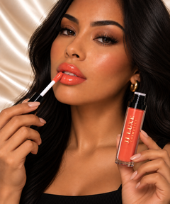 JJ Luxe Cosmetics Heatwave Sheer Peptide Glaze model applying a vivid sheer orange-coral gloss with the doe-foot applicator