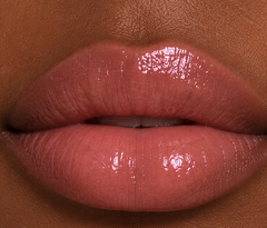 Deep complexion close-up lips wearing JJ Luxe Moonlit sheer blush pink Peptide Lip Glaze with a glossy non-shimmer finish