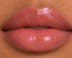 Tan complexion close-up lips wearing JJ Luxe Moonlit sheer blush pink Peptide Lip Glaze with a glossy non-shimmer finish