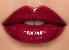 Fair complexion lips wearing JJ Luxe Cosmetics Nocturne Sheer Peptide Glaze in a glossy deep burgundy wine-plum shade.