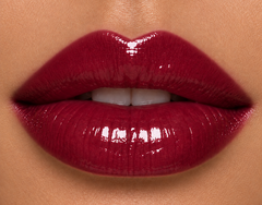 Medium complexion lips wearing JJ Luxe Cosmetics Nocturne Sheer Peptide Glaze in a glossy deep burgundy wine-plum shade.