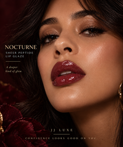 Model wearing JJ Luxe Nocturne Sheer Peptide Lip Glaze in glossy deep burgundy red-plum, shown in a close-up beauty portrait with warm burgundy and gold accents.