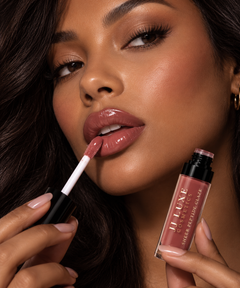 JJ Luxe Cosmetics Slow Burn Sheer Peptide Glaze applied with a doe-foot applicator on medium-deep complexion lips in a glossy dusty rose-mauve shade